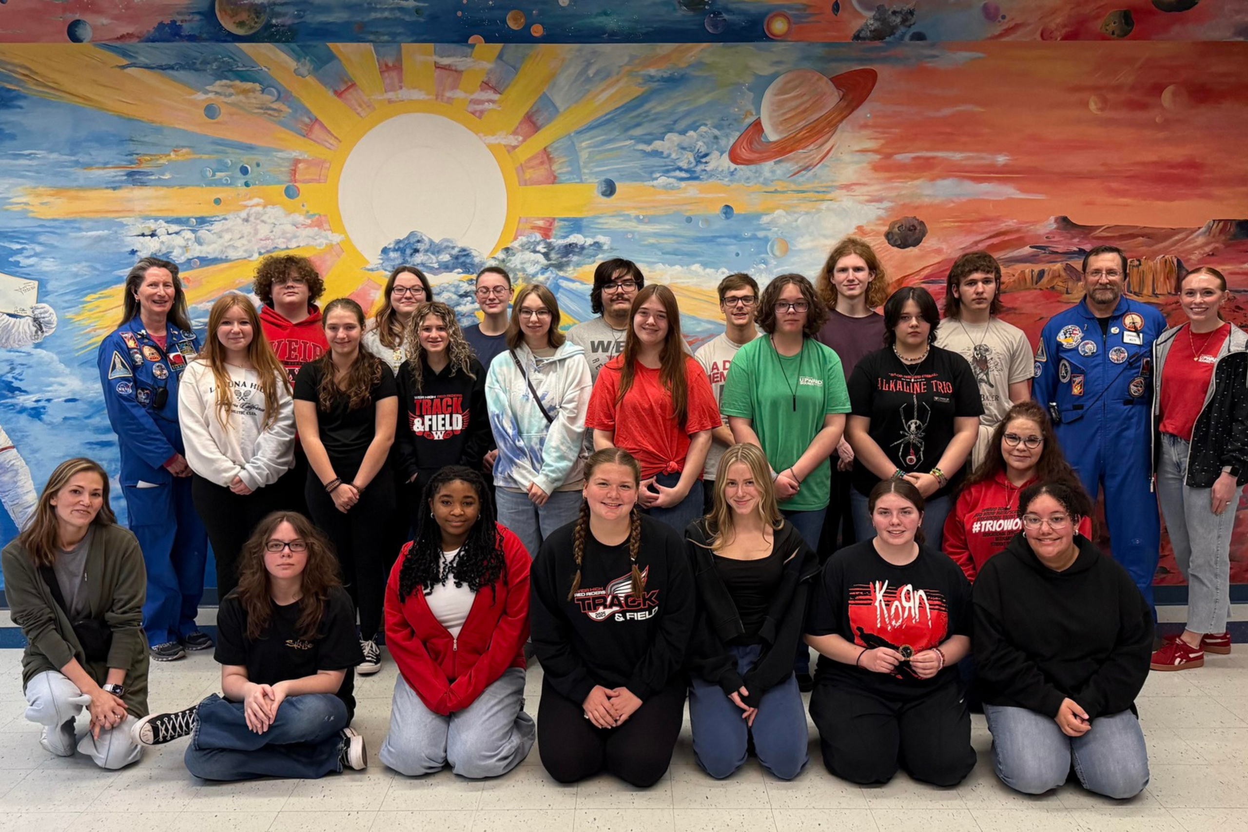 Upward Bond students standing in front of a space mural